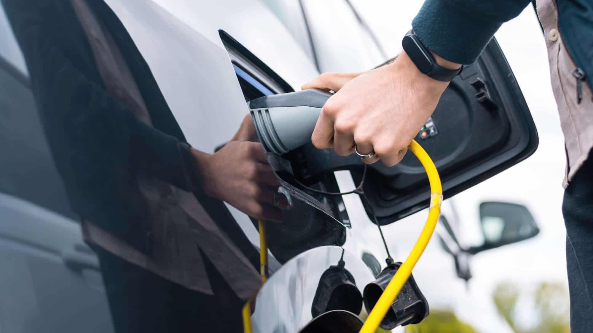 a man plugging charger in an electric car